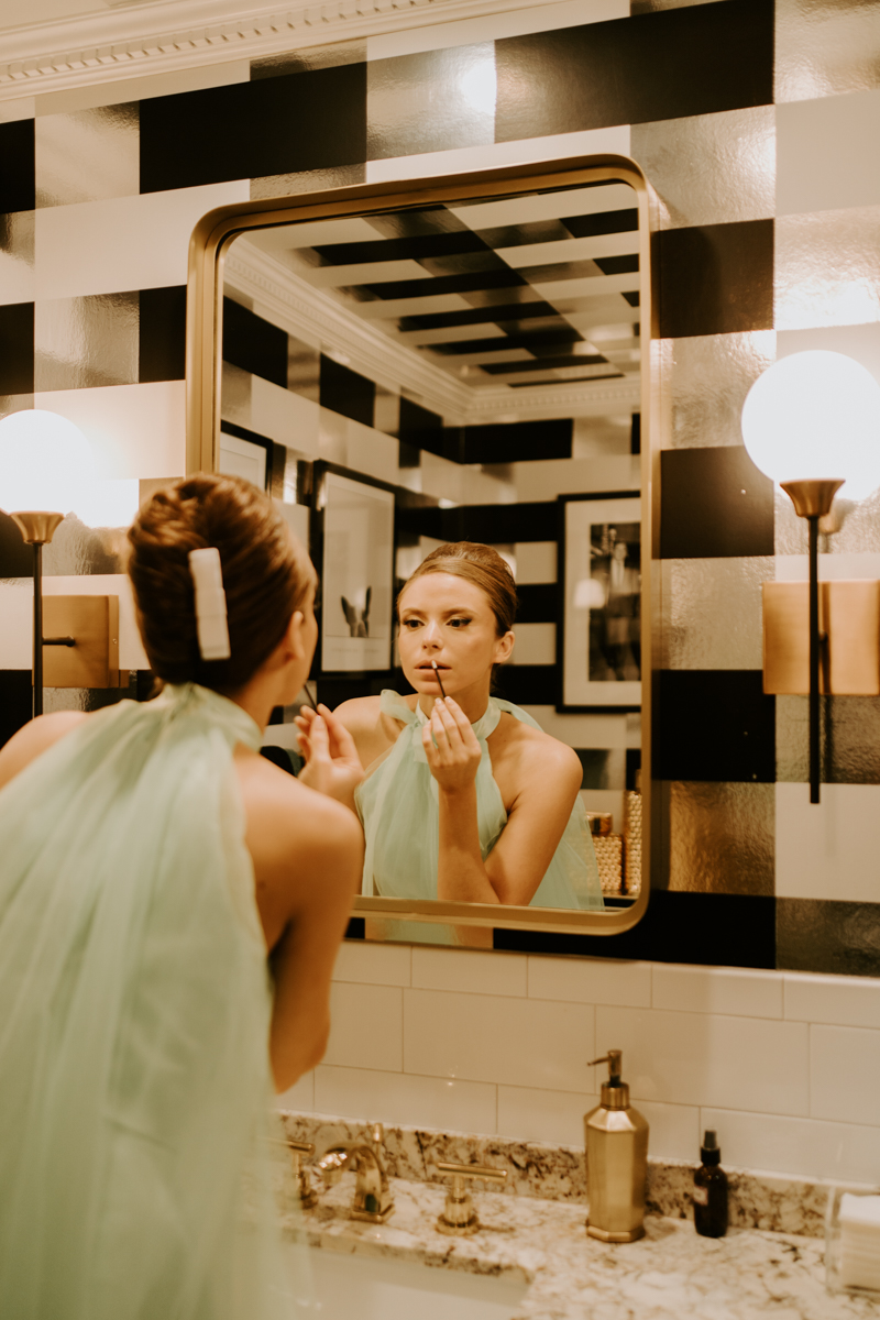 bride wearing vintage dress touching up makeup in mirror