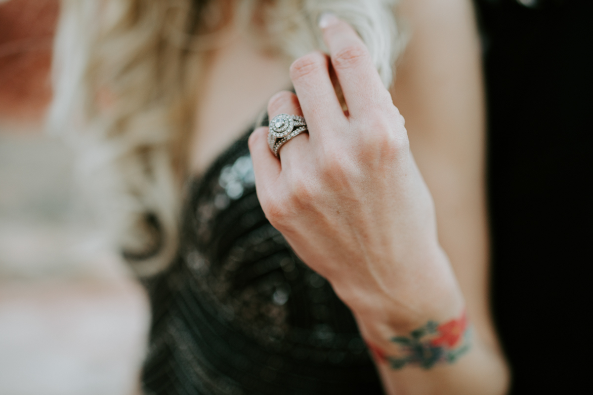 a close up of a woman’s hand and tattooed wrist. she’s wearing a large diamond engagement ring.