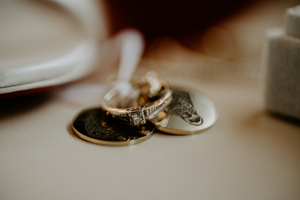 close up image of a diamond engagement ring on top of a pile of coins.